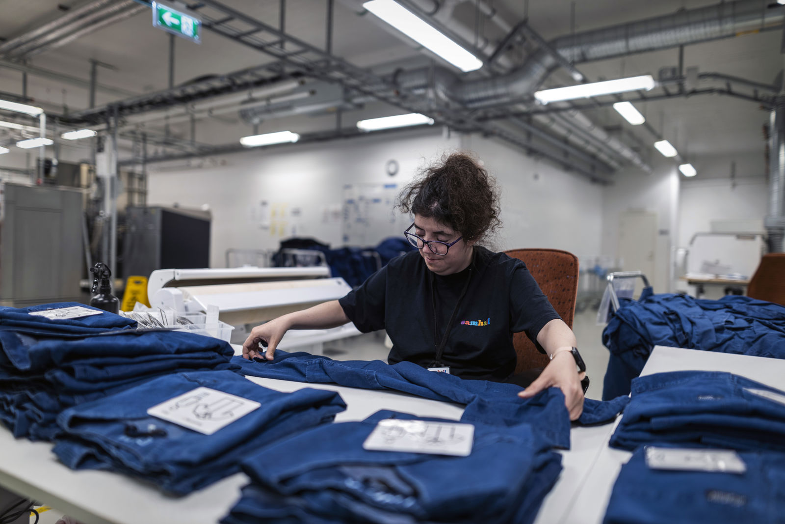 En samhallsanställd sitter vid ett bord och viker ett klädesplagg.