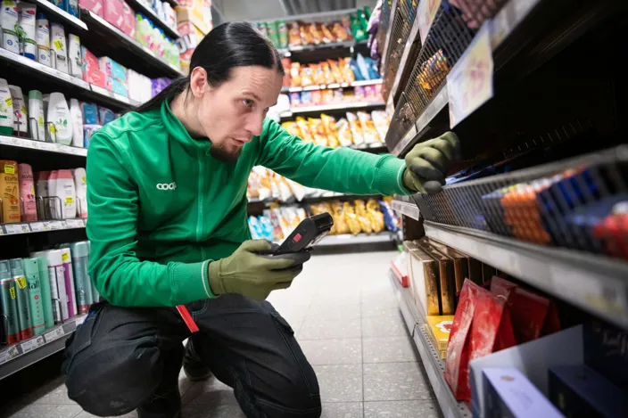 Stefan Vivallius, iklädd grönt, frontar varor och ser till att det ser snyggt ut i matbutiken. 