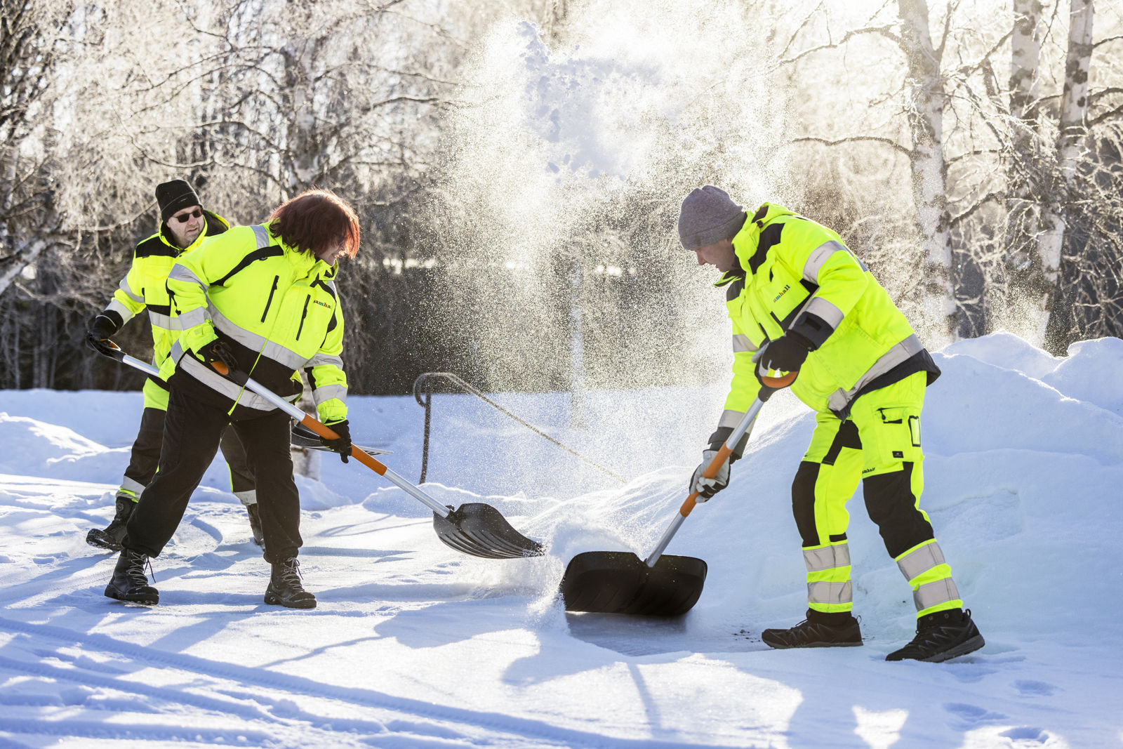 En grupp samhallsanställda i gula jackor skottar snö.