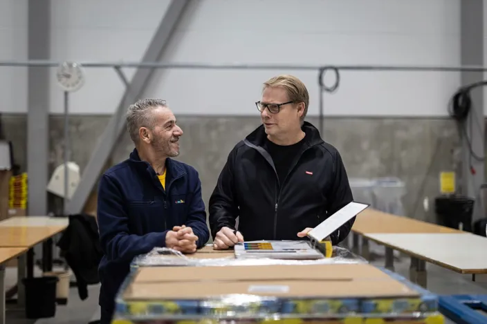 Två män diskuterar på ett lager.