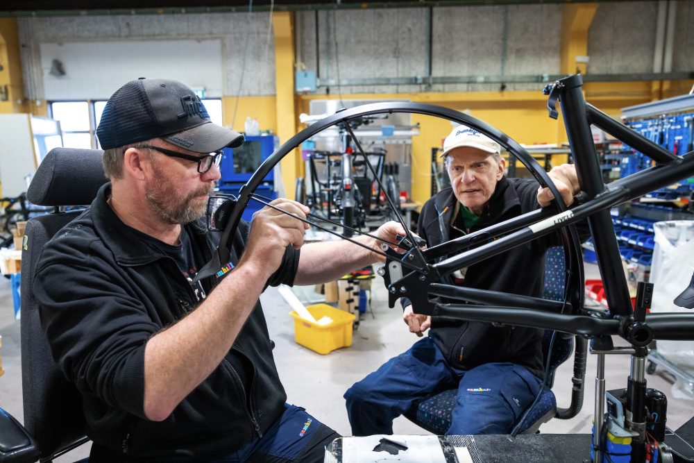 Samhallsmedarbetare reparerar en cykel i en verkstadsmiljö.