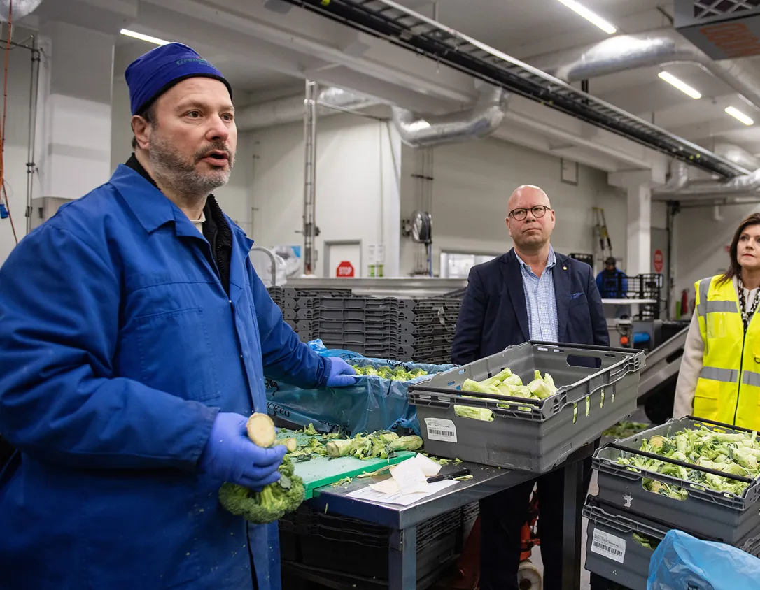 Bild från när Sveriges arbetsmarknadsminister Eva Nordmark och Finlands arbetsminister Tuula Haatainen besökte Grönsaksallen i Sorunda 2021. Vd Christer Läckgren pratar med blåklädda Samhallmedarbetaren Robert under besöket.