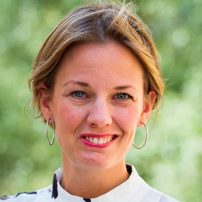 bild på Anna Hagvall som ler och tittar in kameran. Grön bakgrund. 