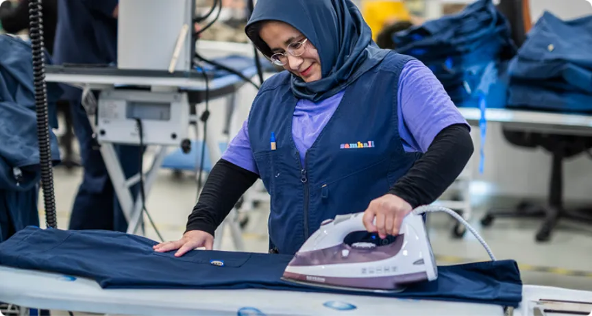 En Samhallmedarbetare stryker ett plagg.