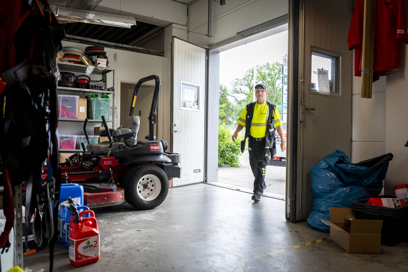 En samhallsanställd i gul väst går in i ett garage.