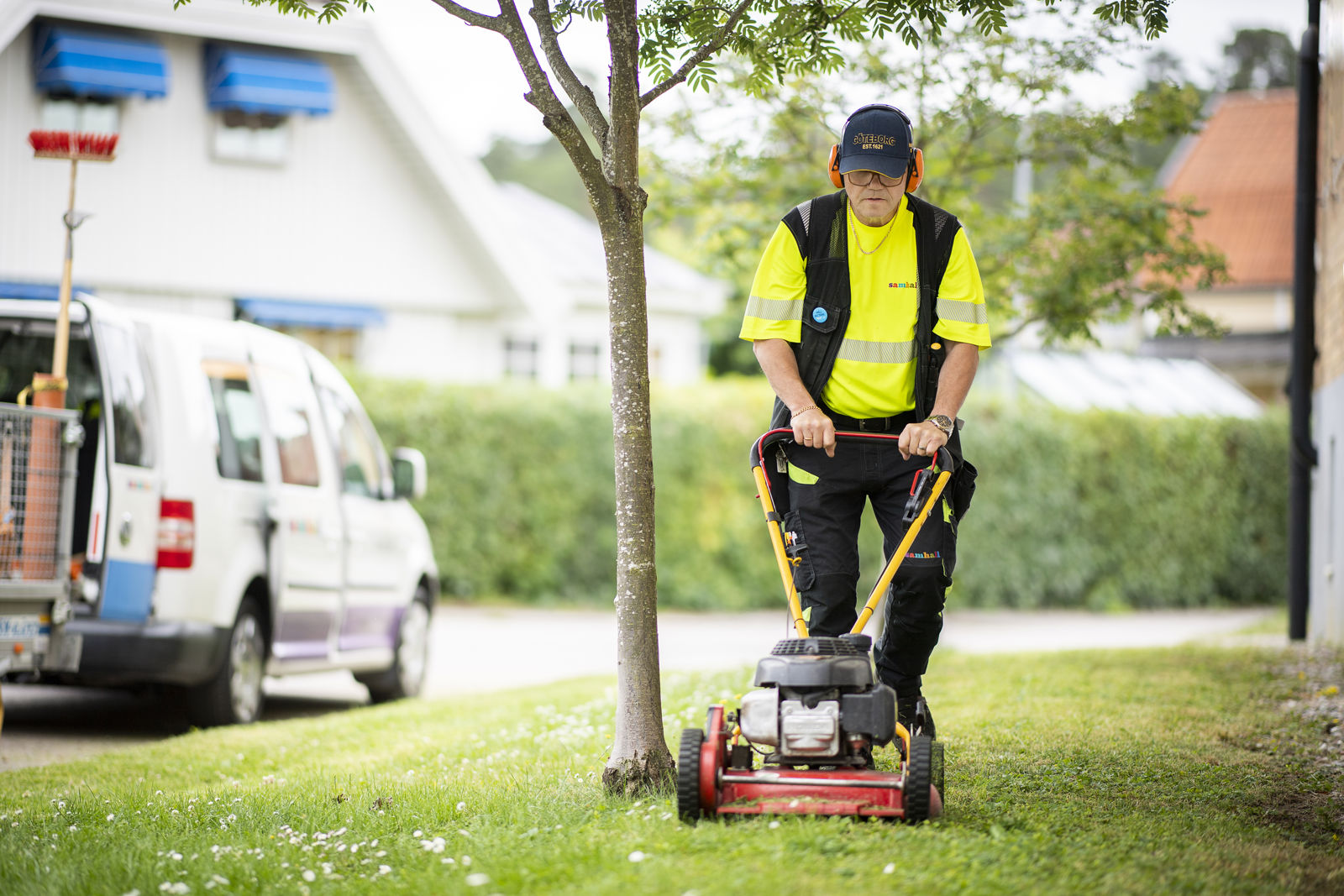 En samhalls anställd klipper gräset med en gräsklippare.