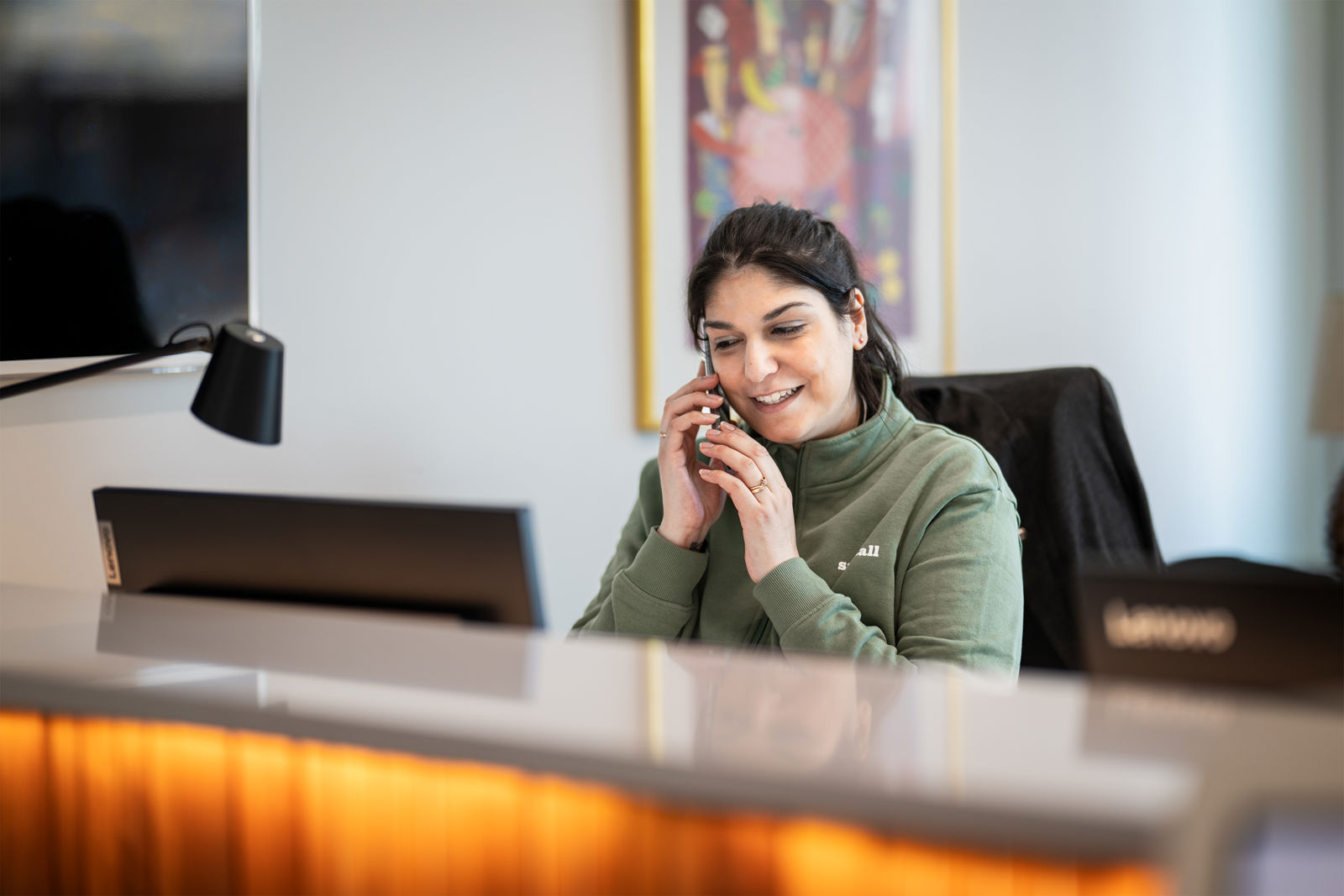 Kvinna sitter vid en reception och pratar i telefon.