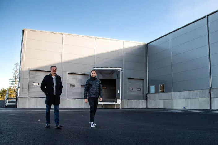 Två män promenerar utomhus utanför lokalen. 