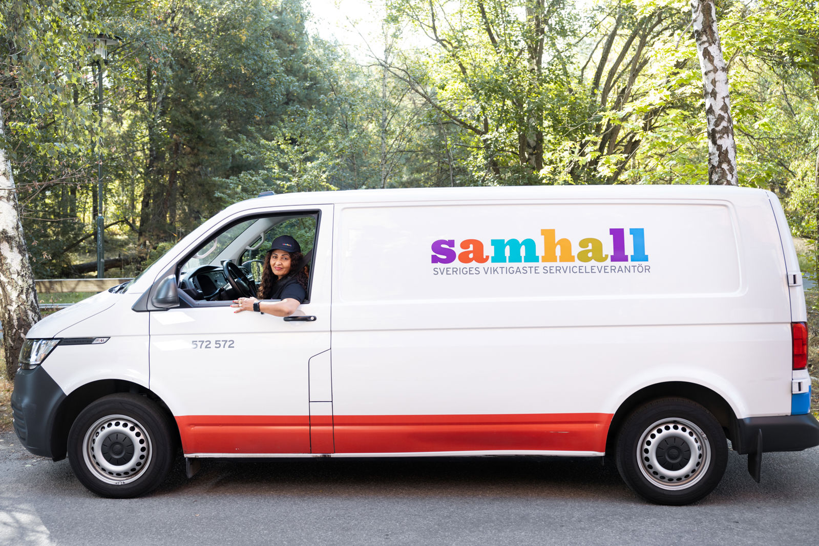 En samhallsanställd som sitter i förarsätet i en vit skåpbil.