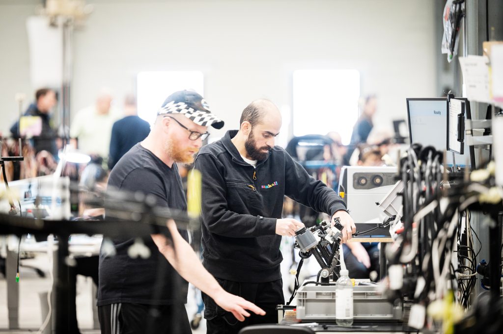 Samhallsmedarbetare arbetar tillsammans vid ett bord i en arbetsmiljö och hanterar material i produktion.