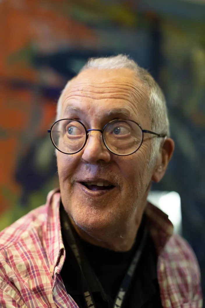 Porträtt på Thomas där han bär en röd rutig skjorta och glasögon