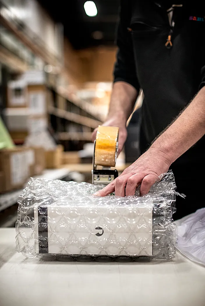 Man ser en persons händer tejpa ihop ett paket.