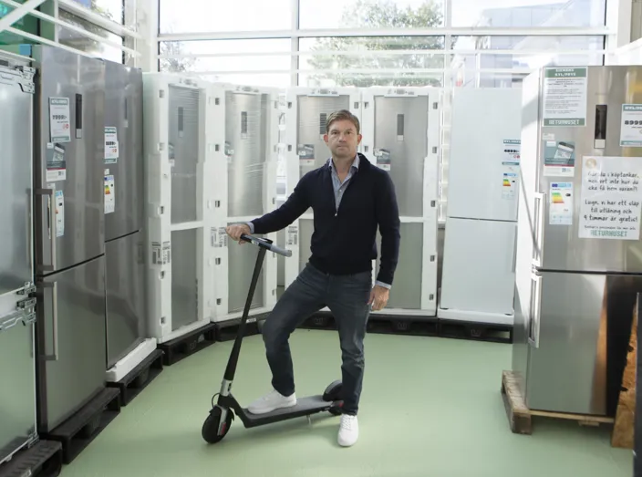 Jon von Knorring står framför några kylskåp. Han håller i en elskoter som ena benet lutas mot.