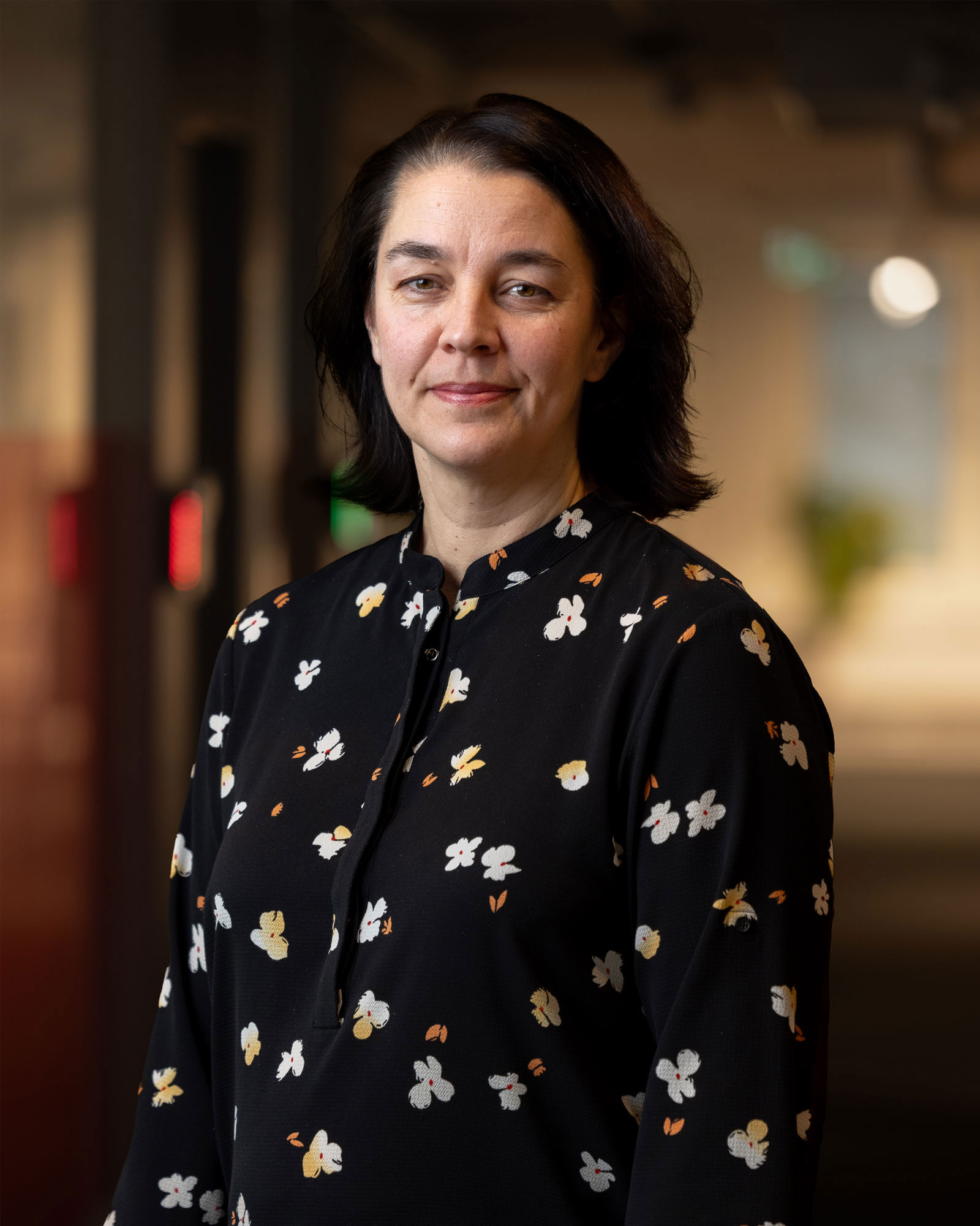 Porträttbild på Sara Revell Ford, VD på Samhall. Fotograferad på Samhalls huvudkontor i Stockholm. Hon har mörkt hår och svart skjorta med blommor på.