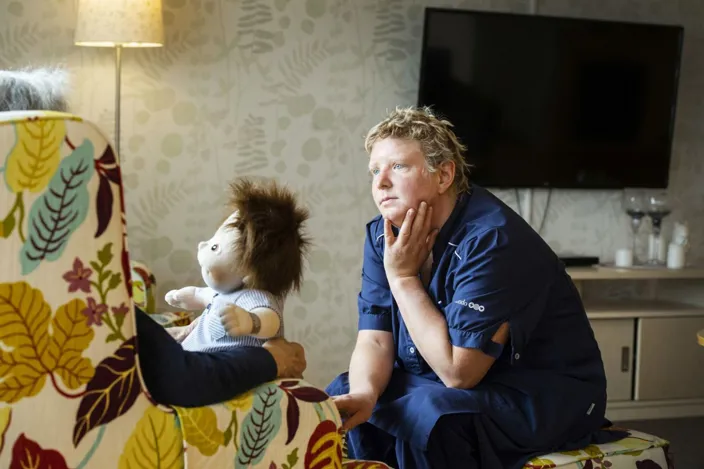 Vårdpersonal lyssnar på en brukare som sitter i en fåtölj