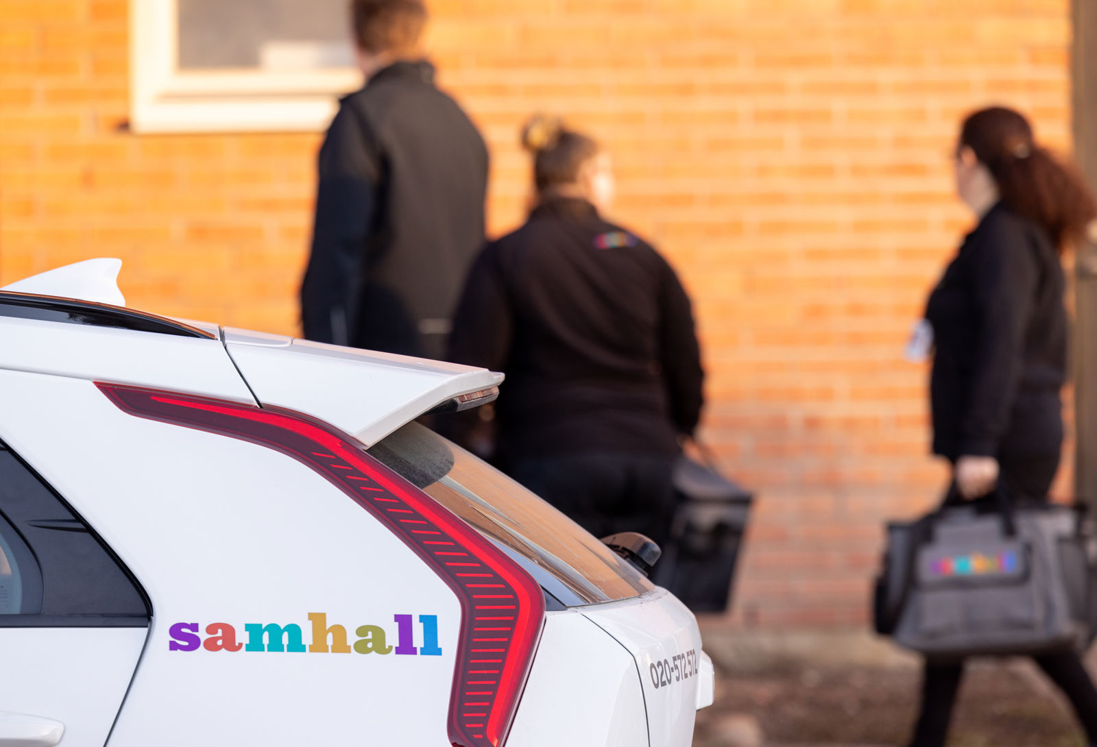 En grupp samhallsanställda som går bakom en vit bil.