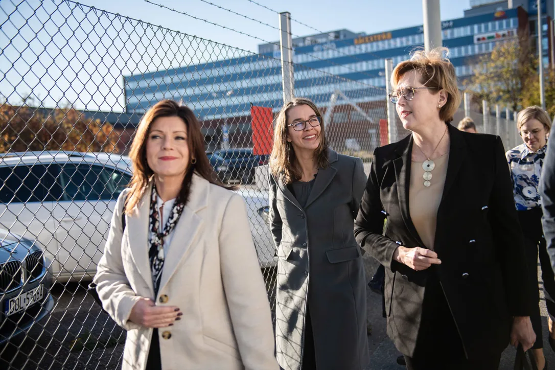 Bild på tre personer som går utomhus vid ett stängsel.