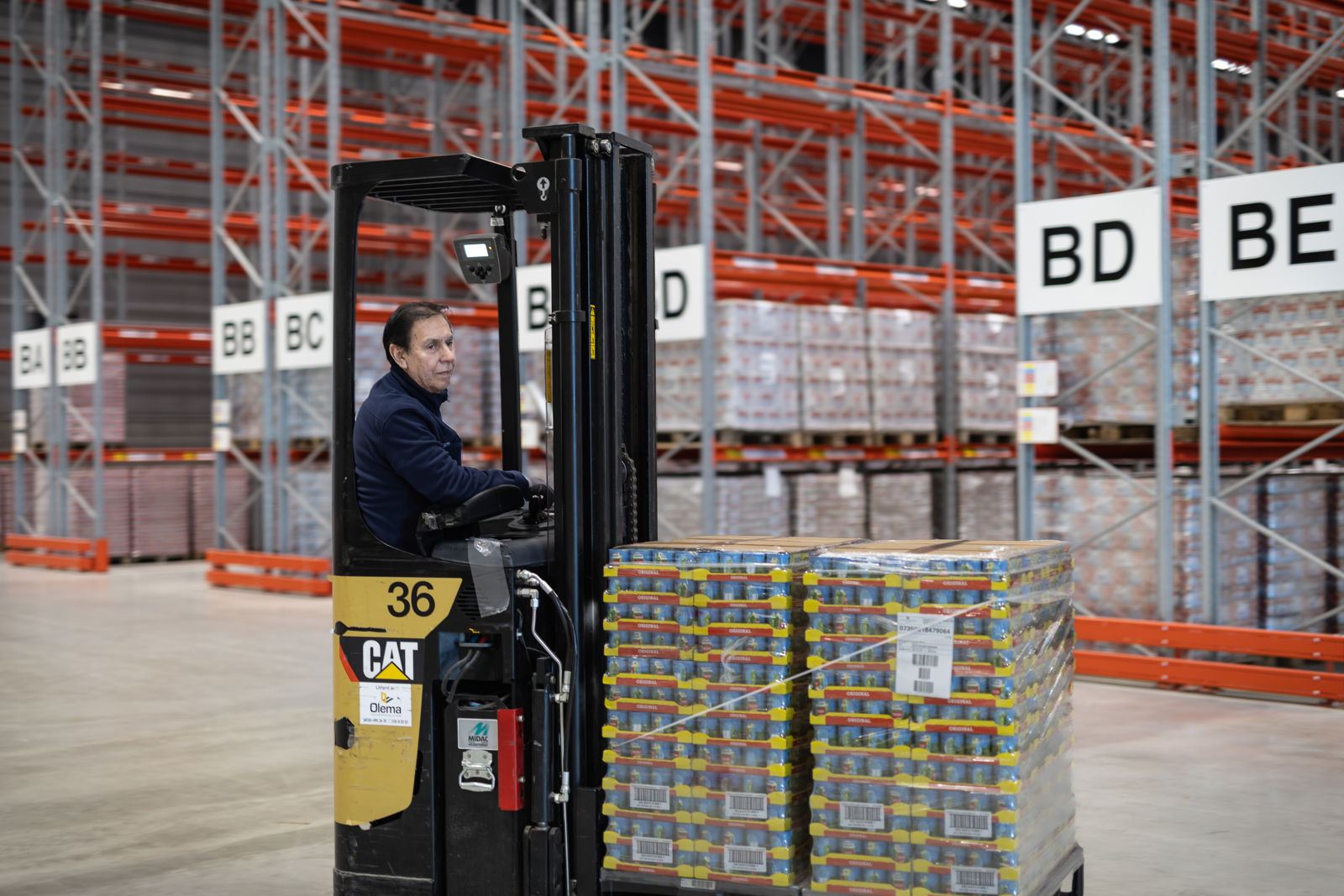 Person kör en truck med lastpallar i ett lager.