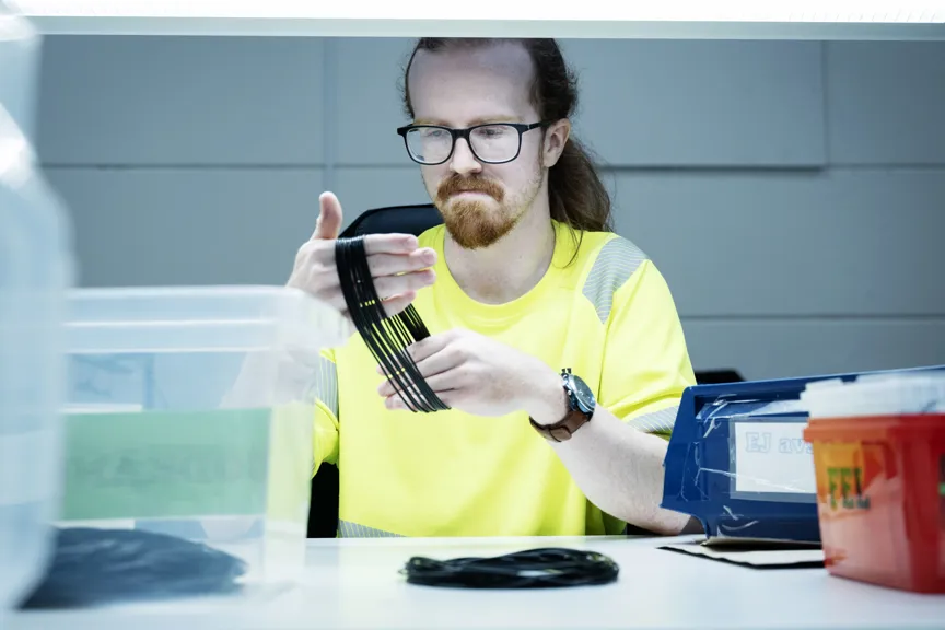 Isak Lundström håller upp flera svarta tätningsringar och granskar dem noggrant vid sin arbetsstation.
