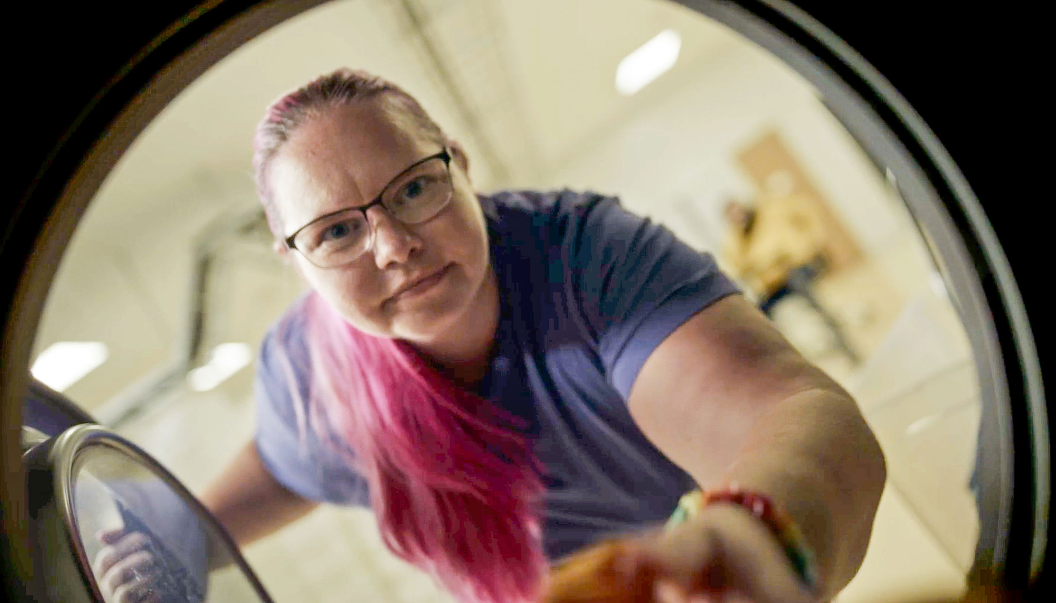 En Samhallsmedarbetare tittar in i en tvättmaskin medan hon arbetar i ett tvätteri.