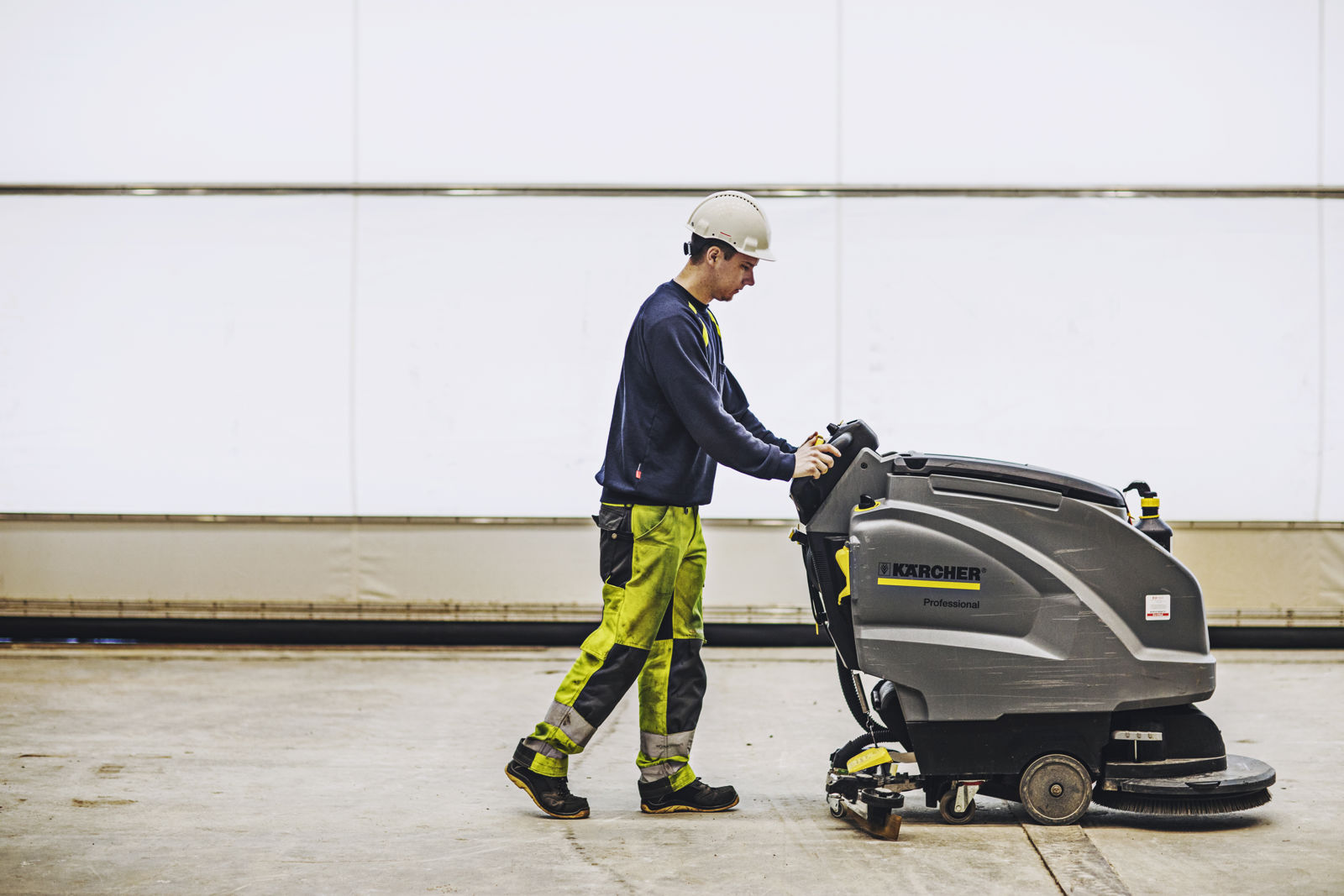  En samhalls-anställd i skyddshjälm använder en maskin.