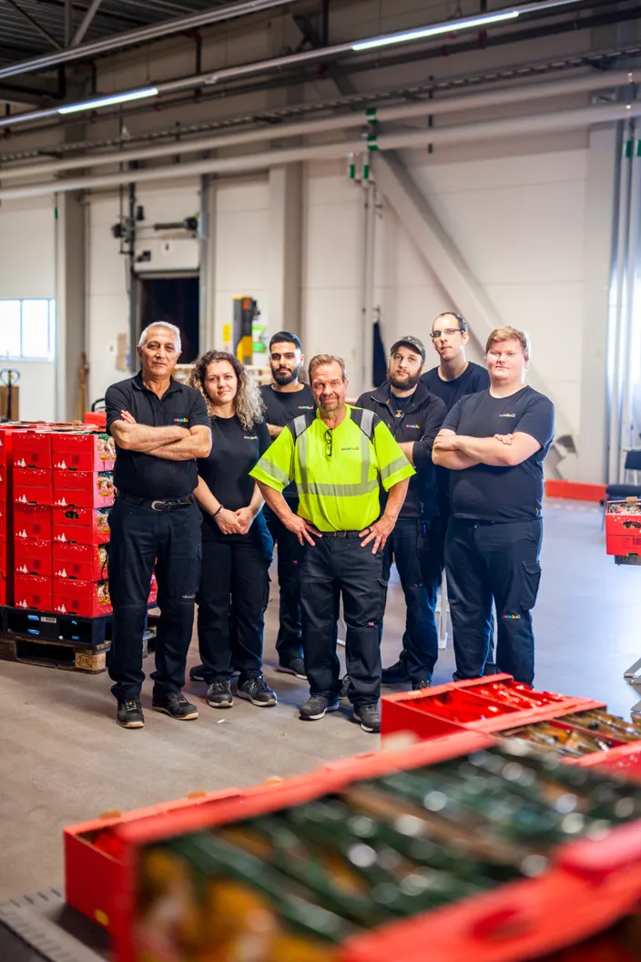 Samhallsmedarbetare sorterar paket vid ett transportband i en logistikmiljö hos PostNord.