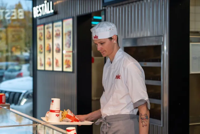 Samhallsmedarbetare serverar mat på en bricka vid disken i en Max-restaurang.