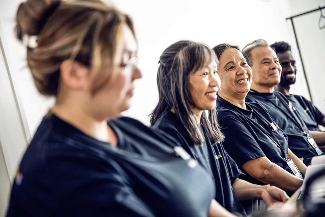 Fem personer från Samhall som sitter på rad och arbetar.