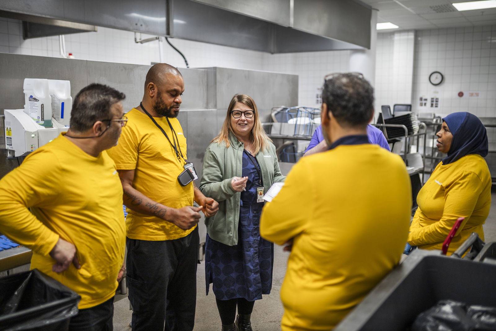 Samhallsmedarbetare samtalar med arbetsledare i en köksmiljö.