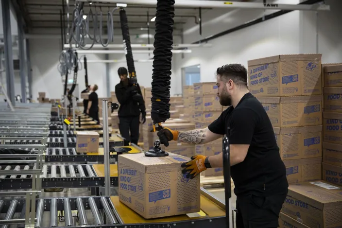 En man använder en lyftmaskin på lagret.