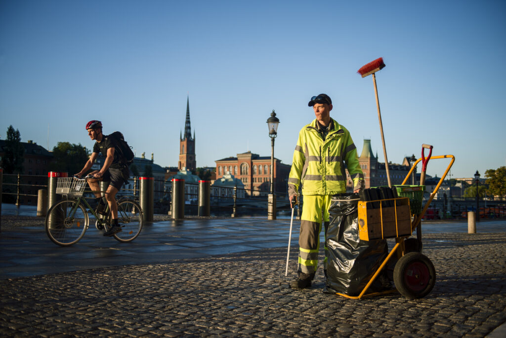 Klockan är 07.07 och Danne är nere vid slutet på Drottninggatan. Han står med verktyg för att städa medan en cyklist cyklar förbi i bakgrunden