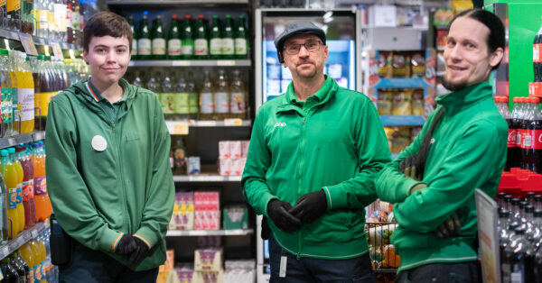 Nora Mångsén, Tony Olaussen och Stefan Vivallius står i en matbutik och tittar in i kameran. De bär gröna arbetskläder på sig. I bakgrunden syns petflaskor uppradade på butikshyllorna.
