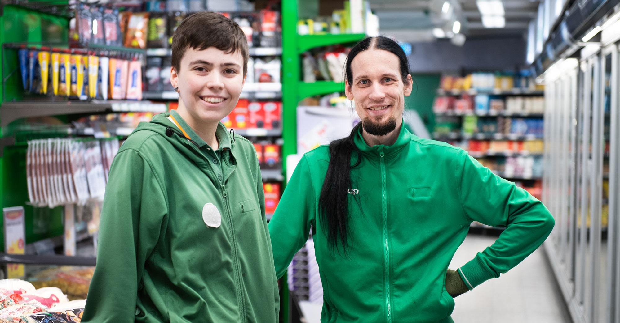 Porträtt av Nora Mångsén och Stefan Vivallius som bär gröna arbetskläder i en matbutik.