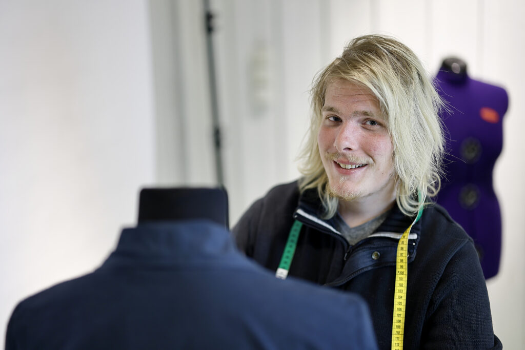 Porträtt på Nicklas Carlsson som hänger kläder på en provdocka.