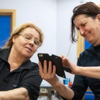 En kvinna visar en annan något på mobilen